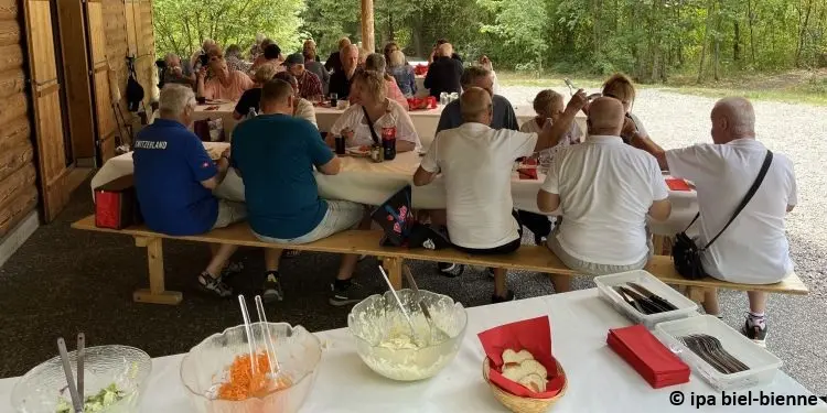 Mitglieder beim Waldhaus an Tischen sitzend